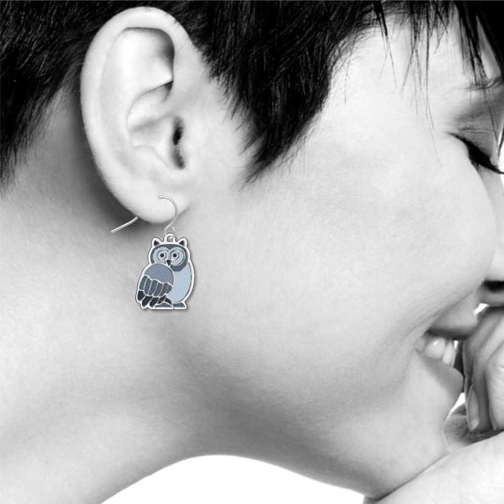 Owls Earrings: silver-tone owl earring inspired by a stained-glass window design, featuring blue, gray, and black owl details shown on model
