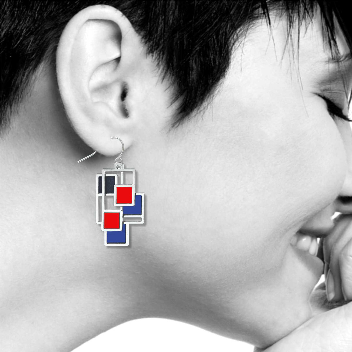 Abstract 1 earrings shown worn, highlighting the geometric Mondrian-inspired design with layered silver-tone shapes and vivid red and blue accents.