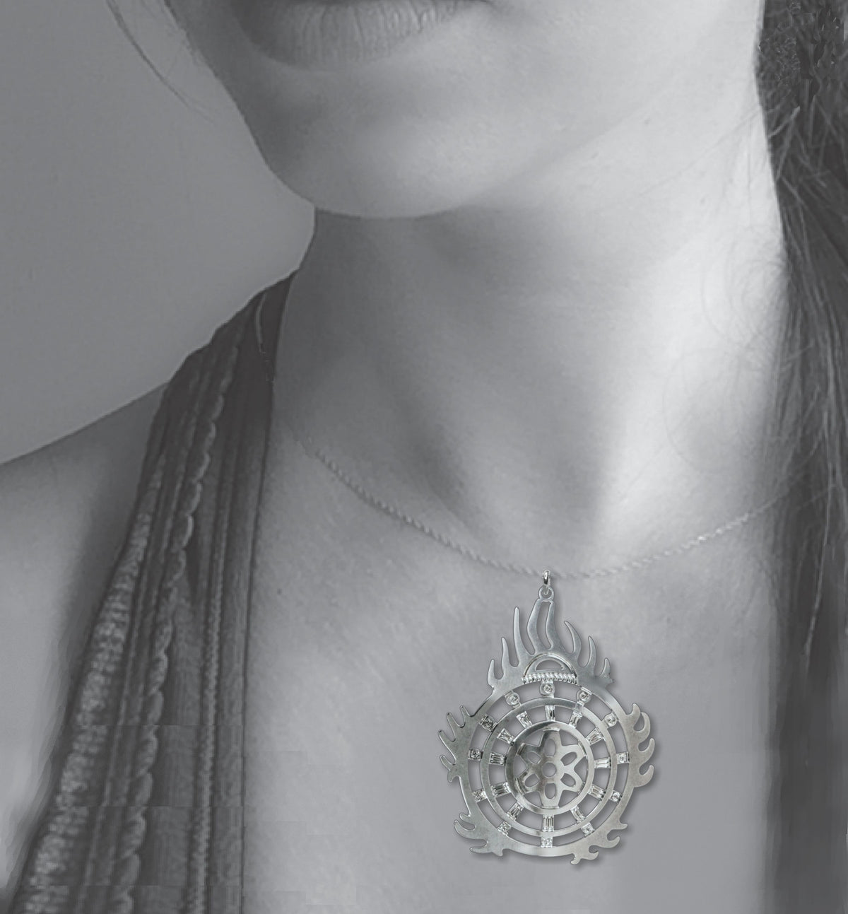 Halo of Flames Necklace worn on a silver chain, featuring a circular silver pendant with flame-like edges, geometric cutouts, and crystal accents displayed against the neckline of a model.
