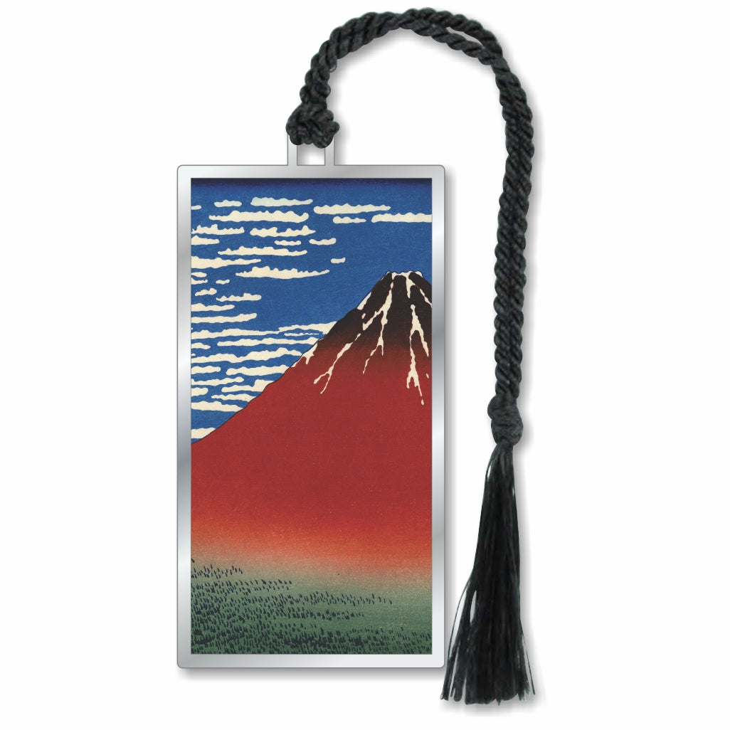 A metal bookmark featuring a print of Mount Fuji with a red peak volcano, blue sky, and white clouds, completed with a black braided tassel for a museum-quality, readers' and art gift.