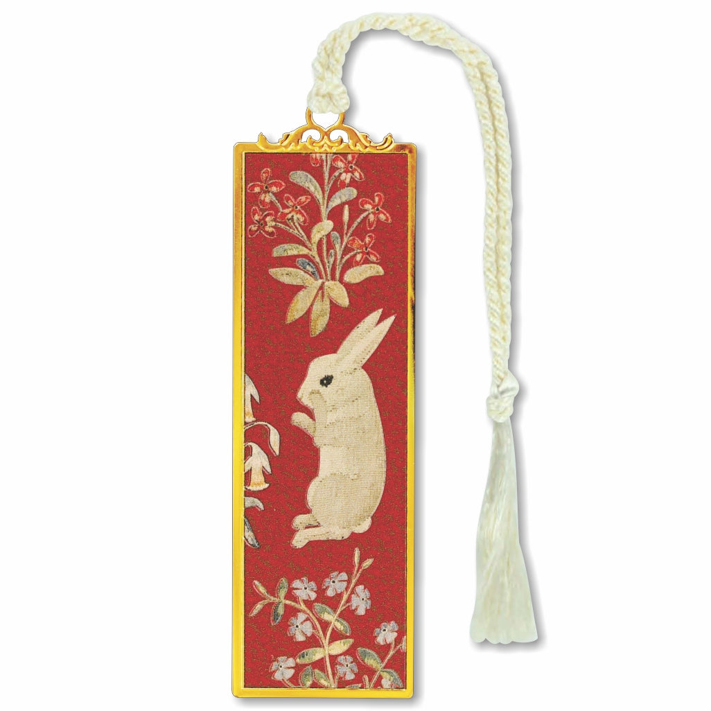 A brass bookmark with a gold finish featuring an illustration of a rabbit, attached to a white cord tassel, on a red background.