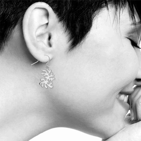 Model wearing Ocean Life dangling earrings featuring abstract silver-tone coral-inspired shapes suspended from fishhook ear wires.