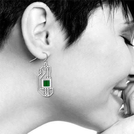 Circuits abstract silver drop earring worn on ear with intricate circuit board-inspired detailing and translucent green geometric accents in a modern industrial design