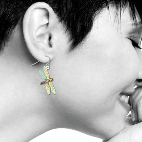 Dragonfly earrings: pastel yellow, green, and blue dragonfly drop earring worn on ear.