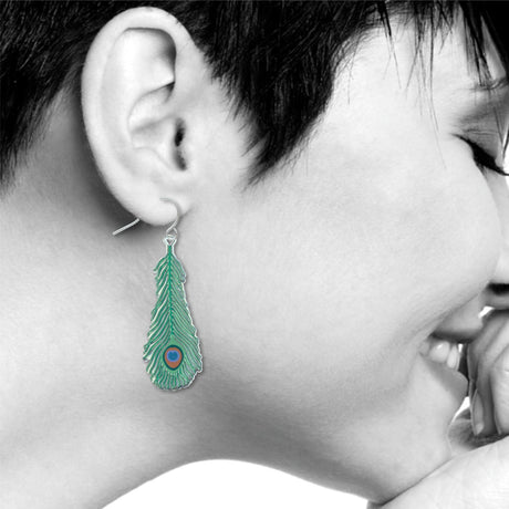 Close-up of a person wearing a peacock feather-shaped earring 