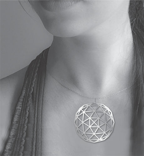 Geodesic Dome necklace shown worn on a model, featuring a large silver-tone geometric pendant with an open triangular dome pattern on a delicate chain.