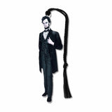 A metal bookmark shaped like Abraham Lincoln with a black tassel, featuring an illustration of Lincoln in his presidential attire.