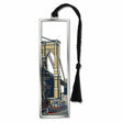 A silver metal bookmark with a depiction of the Brooklyn Bridge and a boat with a black tassel.
