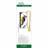 A metal Charley Harper bookmark featuring an illustration of a bird with a yellow-bellied sapsucker on a sycamore tree in a silver frame attached to a golden tassel.