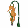 A metal bookmark in the shape of a seahorse with a green tassel, orange brood pouch holding on green sea grass with green braided tassel..